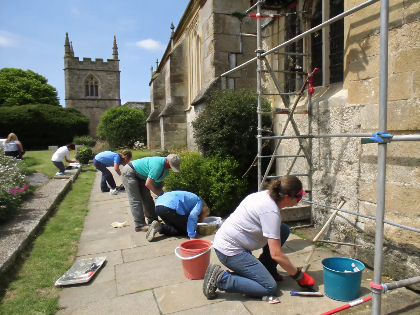 Volunteers cleaning and maintaining a war memorial site, showing their dedication to preserving the memory of the fallen and contributing to the community.